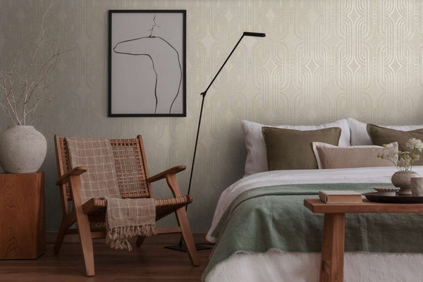 AS Creation French Affair 399371 bedroom with geometric wallpaper in Beige, Gold, Grey, Metallic behind a bed and a woven lounge chair.