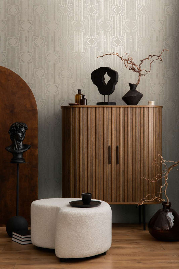 AS Creation French Affair 399371 living room with Beige, Gold, Grey, Metallic geometric wallpaper behind a ribbed wood cabinet and a white ottoman.