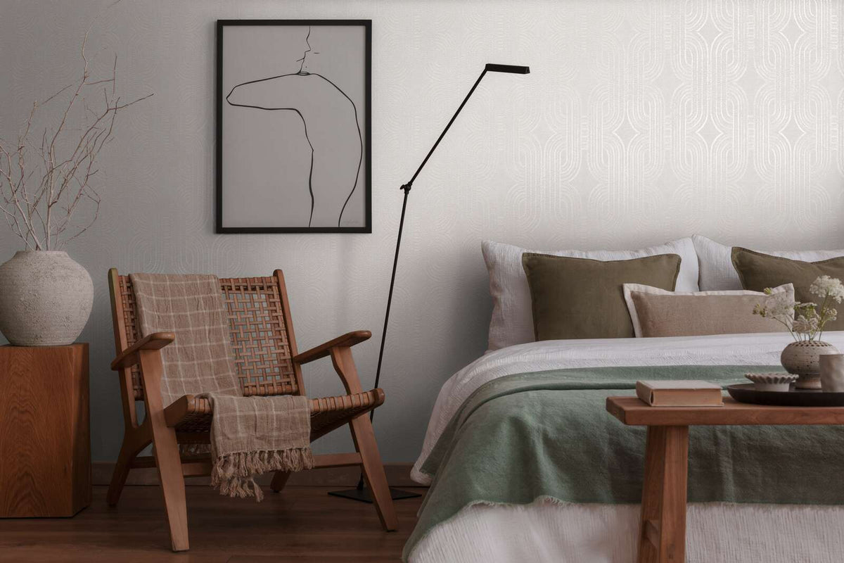 AS Creation French Affair 399372 bedroom with grey and white geometric wallpaper behind a bed and a wooden woven chair.