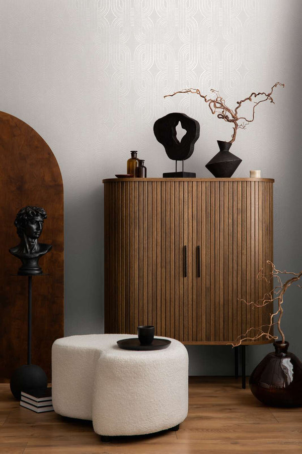 AS Creation French Affair 399372 grey and White geometric wallpaper in a living room behind a wooden cabinet and a white ottoman.