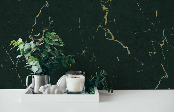 AS Creation Metropolitan Stories Ii 378555 green, Metallic marble vein wallpaper behind a white tray holding a glass candle and a metal jug with greenery on a tabletop.