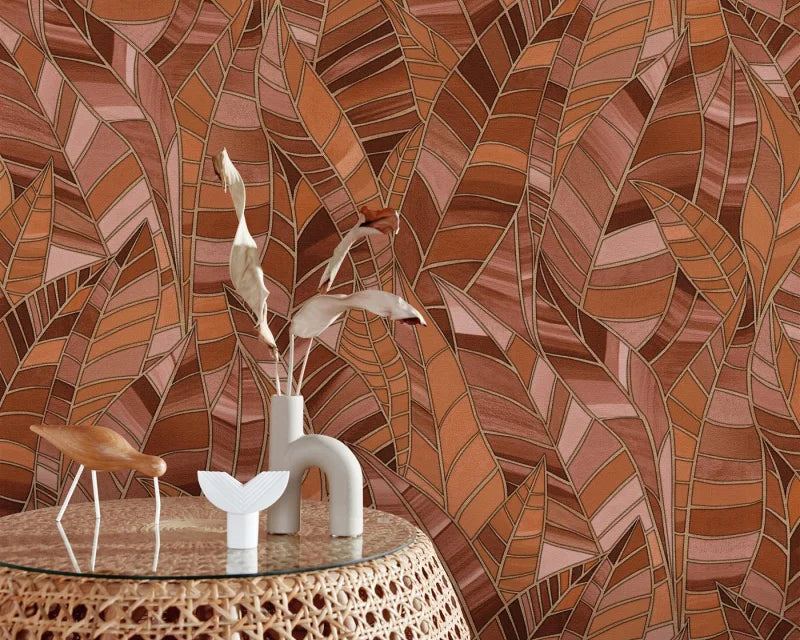 Erismann Elle Decoration 4 terracotta botanical wallpaper with layered leaf pattern and textured finish behind a rattan side table