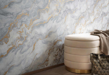 Erismann Elle Decoration 4 marble effect wallpaper in soft grey tones with gold accents styled in a modern interior with upholstered ottoman