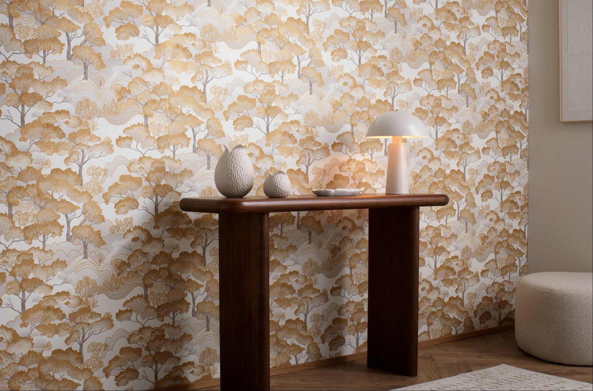 Erismann Elle Decoration 4 scenic tree wallpaper in warm golden tones styled in a modern interior with wooden console table and decorative accents