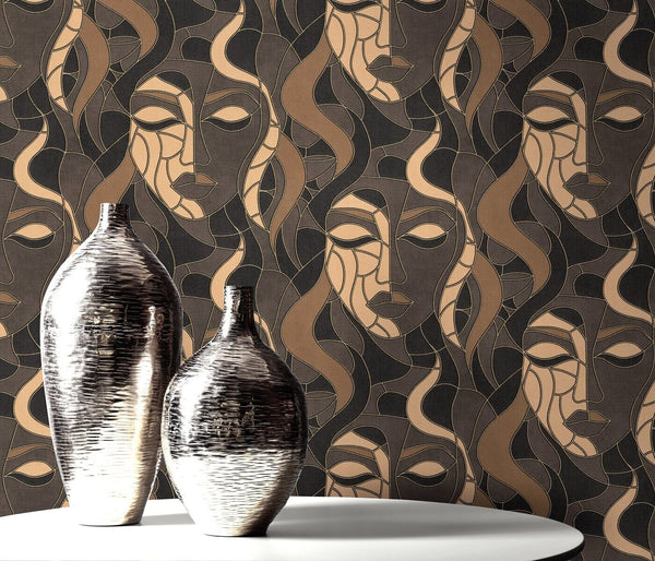 Erismann Elle Decoration abstract face wallpaper in brown and gold tones styled behind a round table and silver vases