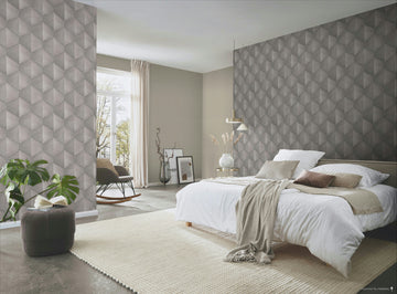 Erismann Fashion For Walls 4 10370-38 wallpaper in a serene bedroom with a geometric feature wall behind the bed, pendant light and side table with a vase, textured rug, rocking chair by the window, and a leafy plant.