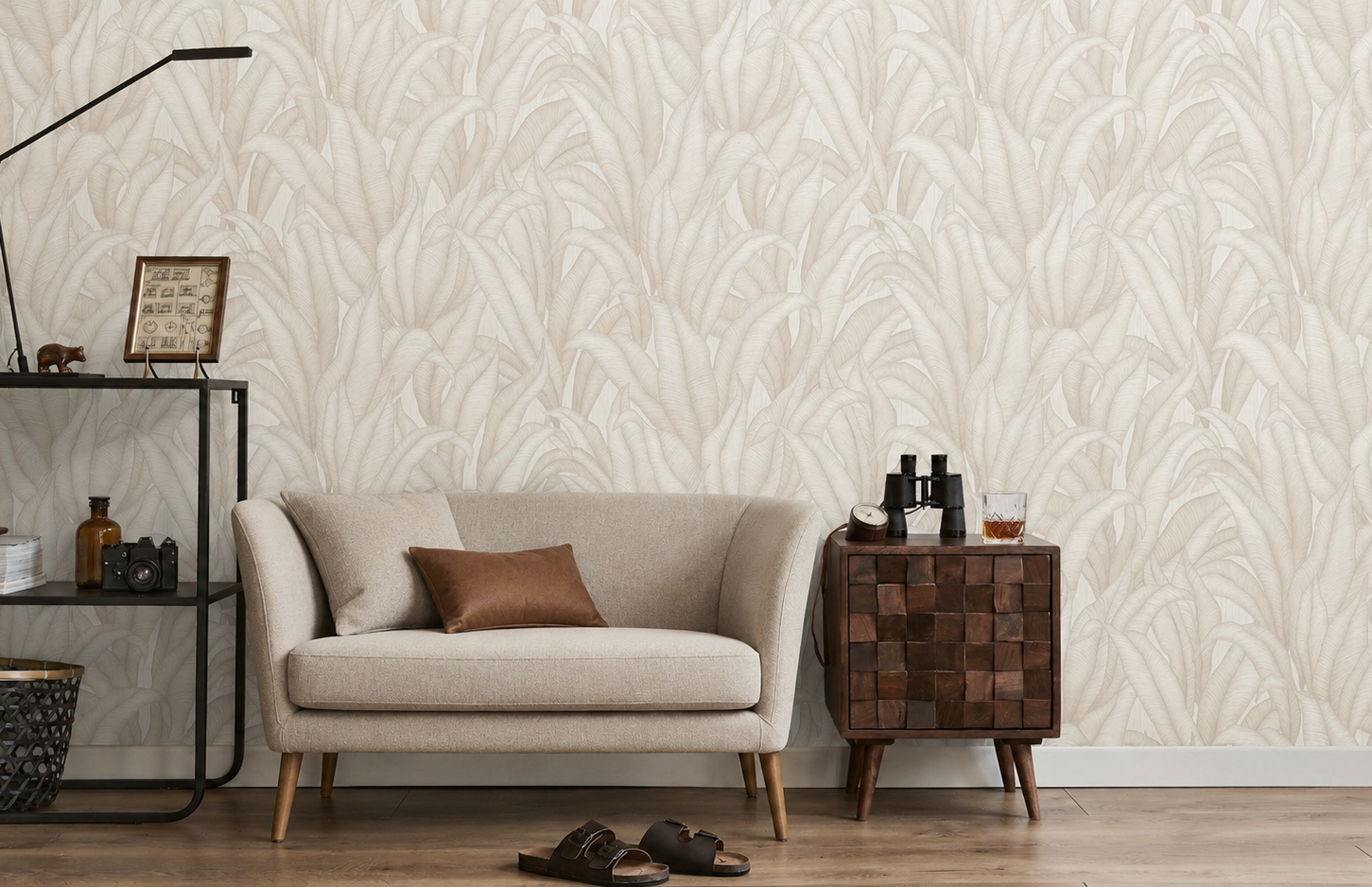 Erismann Fashion For Walls 4 10371-26 wallpaper lounge feature wall with subtle leaf pattern behind a compact sofa, wood side cabinet, and metal shelving with floor lamp, creating a calm relaxed feel.