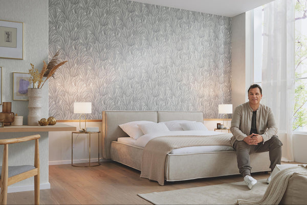 Erismann Fashion For Walls 4 10371-31 wallpaper bedroom feature wall behind upholstered bed, twin bedside lamps, framed art and desk nook, large window with sheer curtains, calm airy mood.