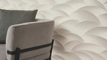Erismann Fashion For Walls 4 10372-38 wallpaper lounge feature wall with curved layered pattern behind a ribbed upholstered armchair and cushion, calm modern mood.