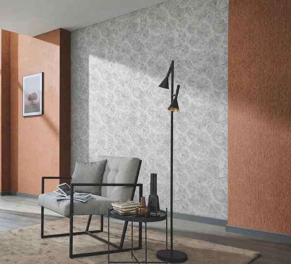 Erismann Fashion For Walls 4 10373-10 wallpaper in a modern lounge feature wall behind a gray armchair, black floor lamp, round side table with books and vases, and a framed print, creating a calm relaxed mood.
