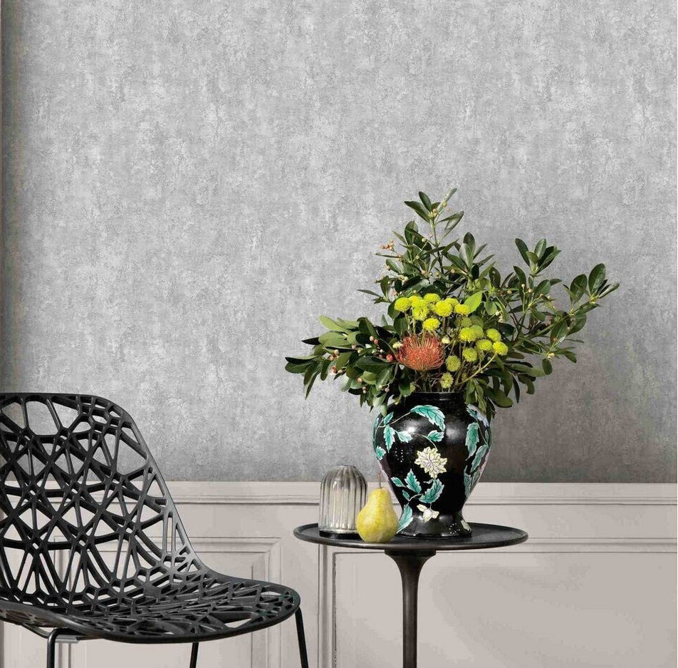 Erismann Fashion For Walls 4 10375-31 wallpaper lounge feature wall above paneling with a black lattice chair, small round side table, and leafy floral vase, modern relaxed mood.
