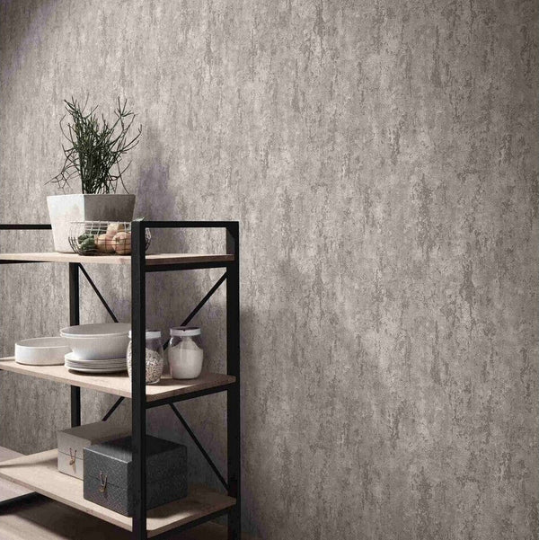 Erismann Fashion For Walls 4 10375-38 wallpaper lounge feature wall with textured concrete-look surface beside black metal and wood shelving holding a potted plant, crockery and storage boxes, creating a calm minimalist vibe.