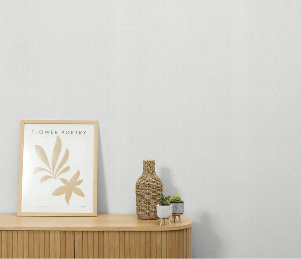 Erismann Forest Dreams 10559-02 wallpaper on a light textured wall above a wooden cabinet with framed art, vase, and small plants.