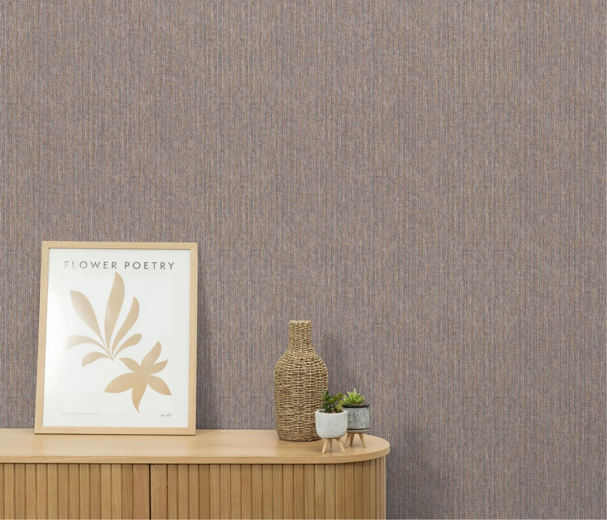 Erismann Forest Dreams 10559-22 wallpaper on the wall behind a wooden dresser with framed art, woven vase, and small plants.