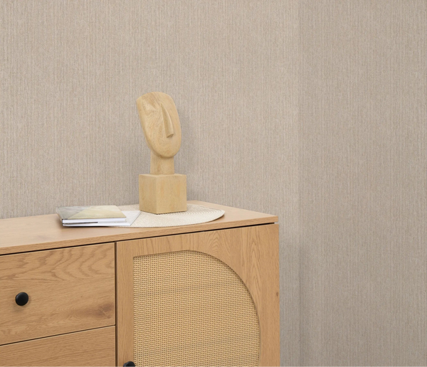 Erismann Forest Dreams 10559-32 wallpaper on the wall behind a wooden chest of drawers with sculpture and stacked books.