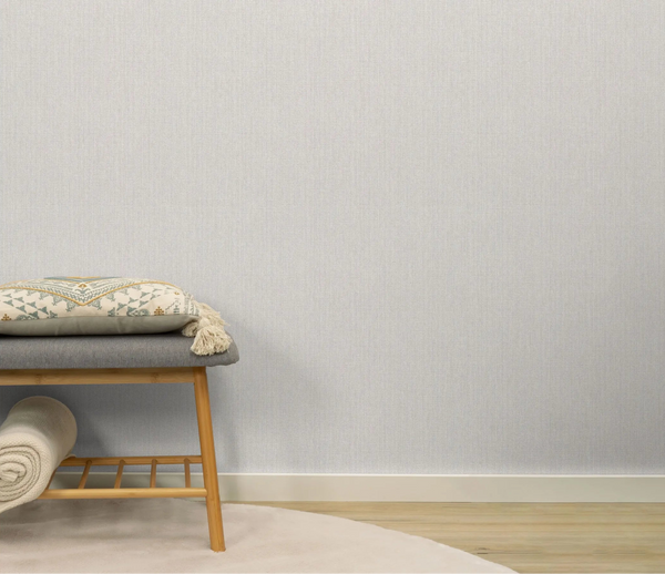 Erismann Forest Dreams 10559-37 wallpaper on a pale textured wall behind a bench with patterned cushion and rolled throw.