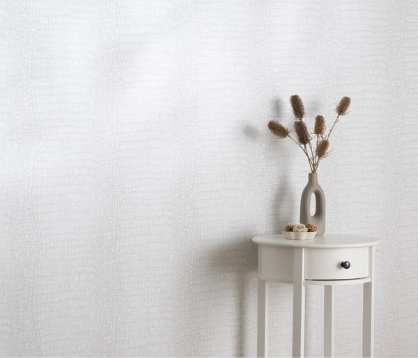 Erismann Forest Dreams 10560-10 wallpaper with subtle pale reptile texture behind a white side table and dried floral vase.