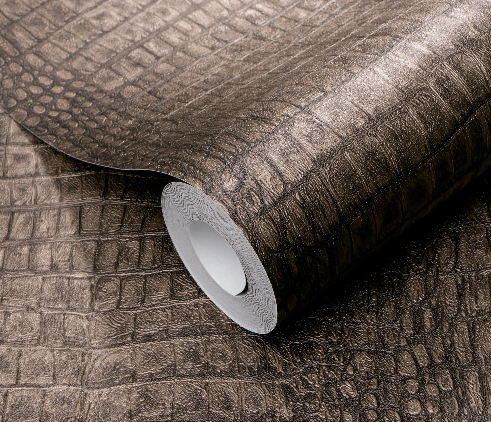 Erismann Forest Dreams 10560-11 wallpaper roll close-up with dark reptile-skin texture and raised rectangular scale pattern.