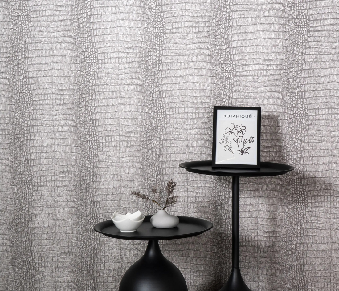 Erismann Forest Dreams 10560-37 wallpaper on a grey reptile-skin textured wall behind black pedestal tables and framed botanical print.