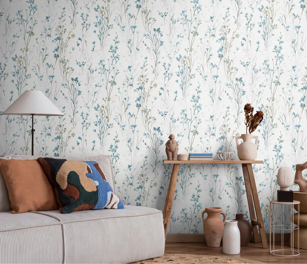 Erismann Forest Dreams 10561-18 wallpaper with delicate blue wildflower stems behind a sofa, floor lamp, and wooden console table.