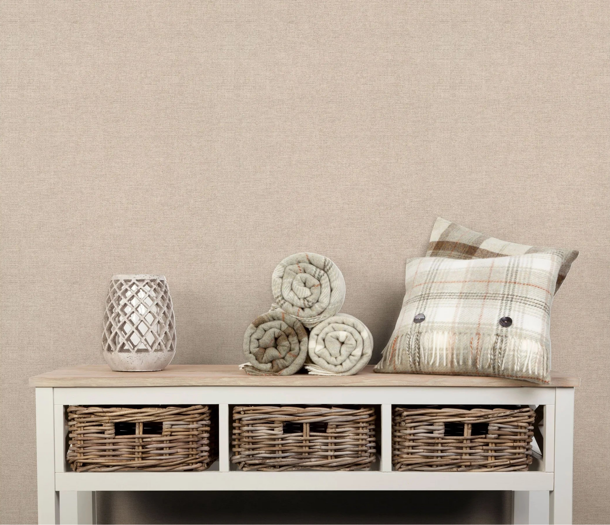 Erismann Forest Dreams 10563-02 wallpaper a neutral textured wall behind a console table with baskets, rolled blankets, a lantern, and a plaid cushion.