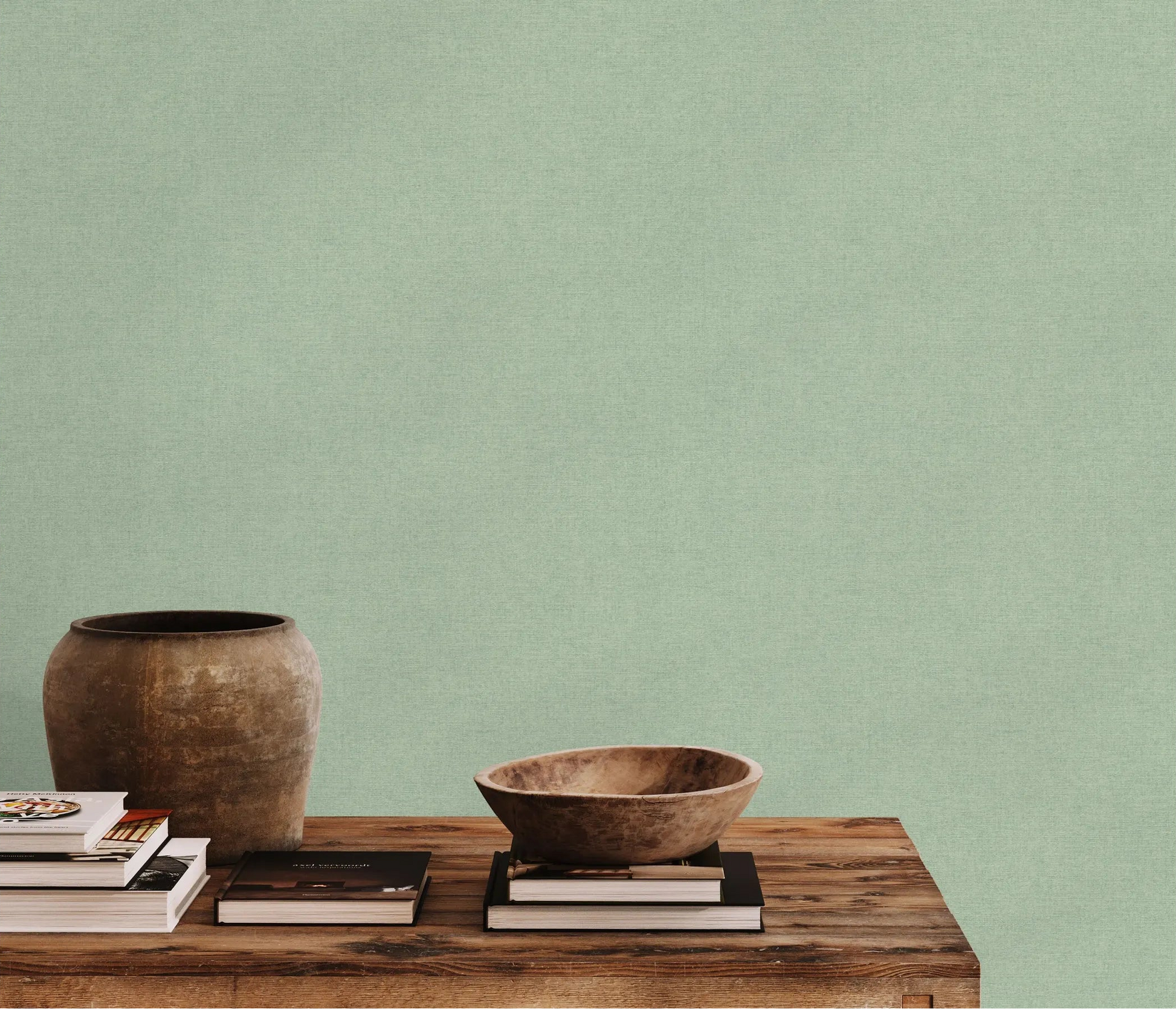 Erismann Forest Dreams 10563-07 wallpaper on a pale green textured wall behind a wooden table with books and rustic bowls.