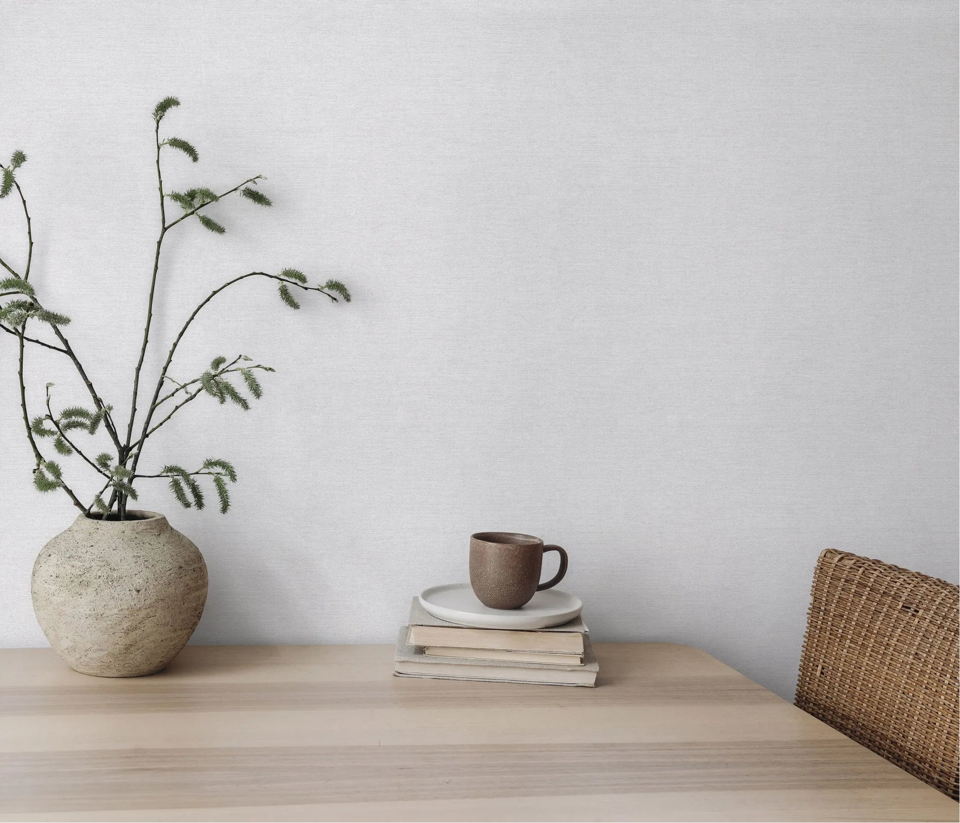 Erismann Forest Dreams 10563-10 wallpaper on a softly textured wall behind a vase, books, mug, and wicker chair.
