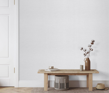 Erismann Forest Dreams 10563-10 wallpaper on the wall behind a wooden bench with books, vase, cotton stems, pouf, and hat.