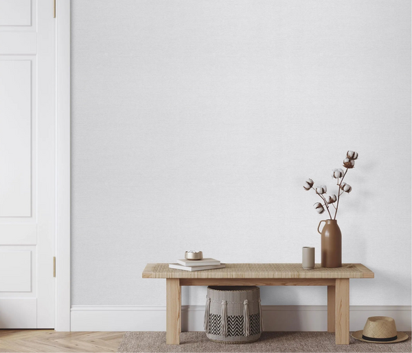Erismann Forest Dreams 10563-10 wallpaper on the wall behind a wooden bench with books, vase, cotton stems, pouf, and hat.