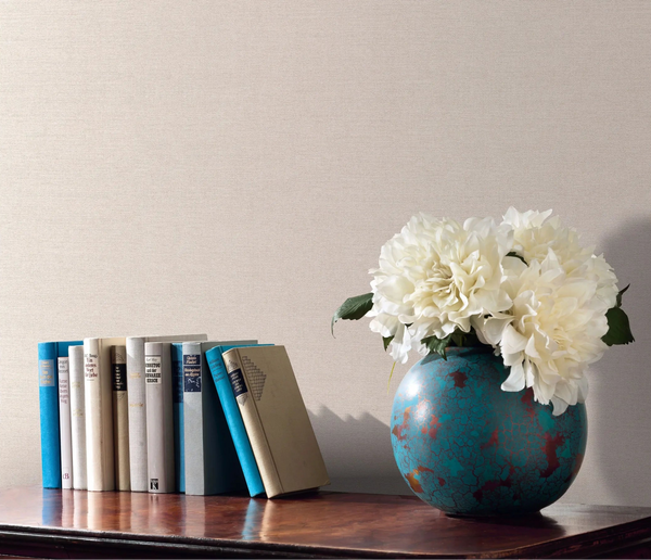 Erismann Forest Dreams 10563-14 wallpaper on a textured neutral wall behind books and a turquoise vase of white flowers.