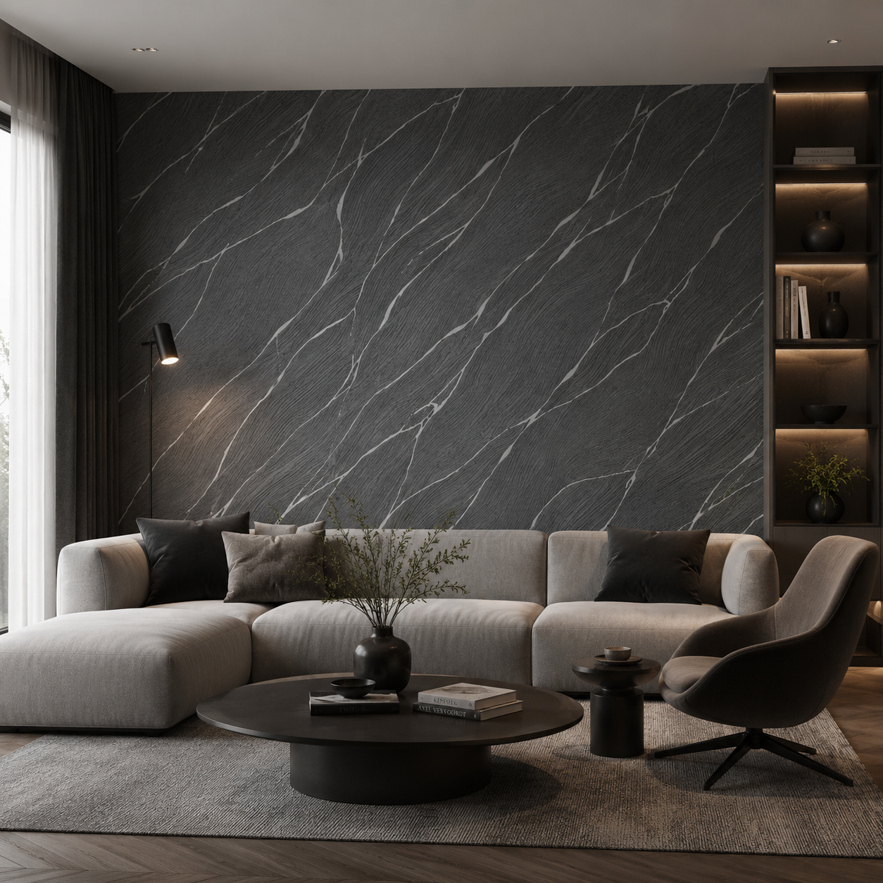Erismann Opus 10440-15 charcoal marble-effect wallpaper on a dramatic living room feature wall with a light sectional sofa, black coffee table, dark shelving, and moody contemporary styling.