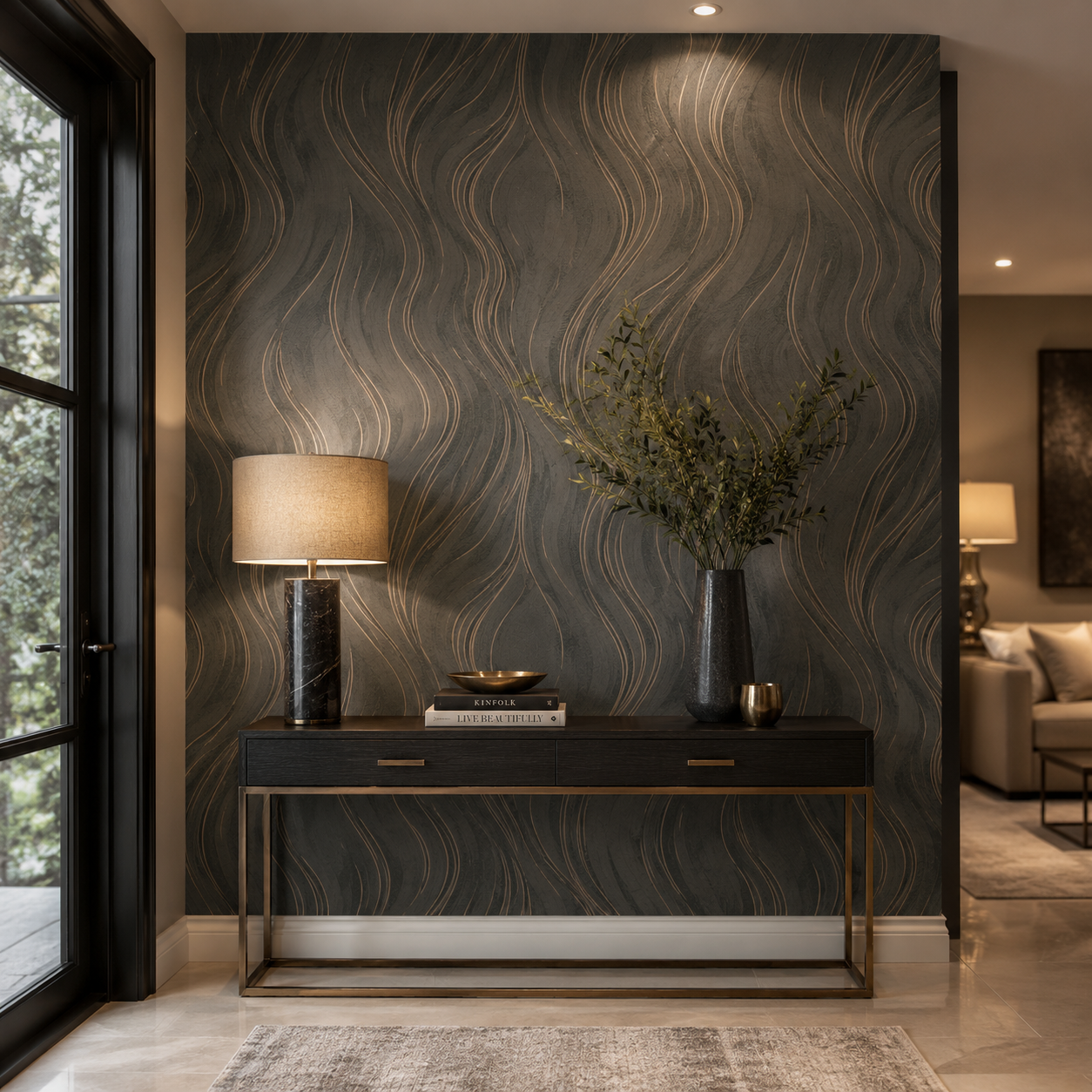 Erismann Opus 10456-11 charcoal and bronze abstract wave wallpaper in a refined entryway with a black console table, brass frame detail, warm lamp lighting, greenery, and dark contemporary styling.