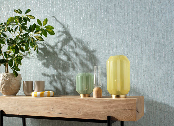 Styled room with Erismann Secret Garden textured wallpaper on the wall behind a wood console and decorative accents.
