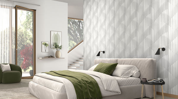 Erismann Elysium textured geometric wallpaper in soft white tones, installed as a feature wall in a modern bedroom, adding subtle depth and architectural interest while complementing neutral furnishings and green accents for a calm, contemporary atmosphere.