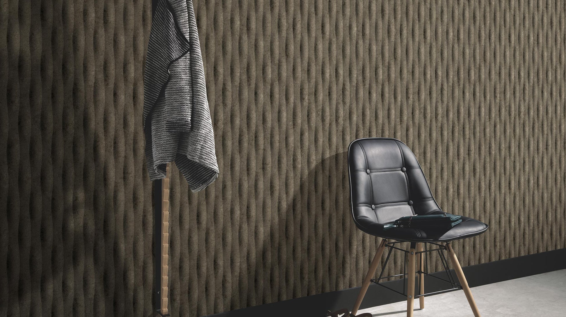 Erismann Fashion for Walls 5 textured vertical stripe wallpaper in dark brown tones styled in a modern interior with a black chair and minimalist décor.