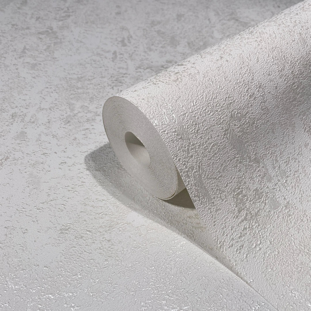 Marburg Avalon 31645 Close-up of a white textured wallpaper roll with an irregular plaster-like pattern, partially unrolled on a matching surface.