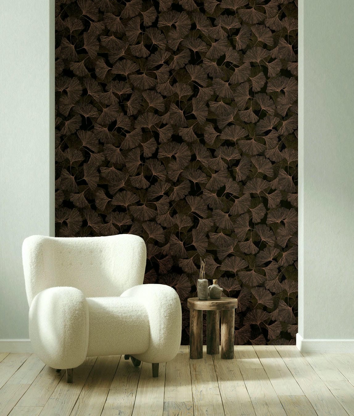 Marburg Boho 35779 Dark brown ginkgo leaf wallpaper on a feature wall behind a white armchair and a small wooden side table on light wood flooring.