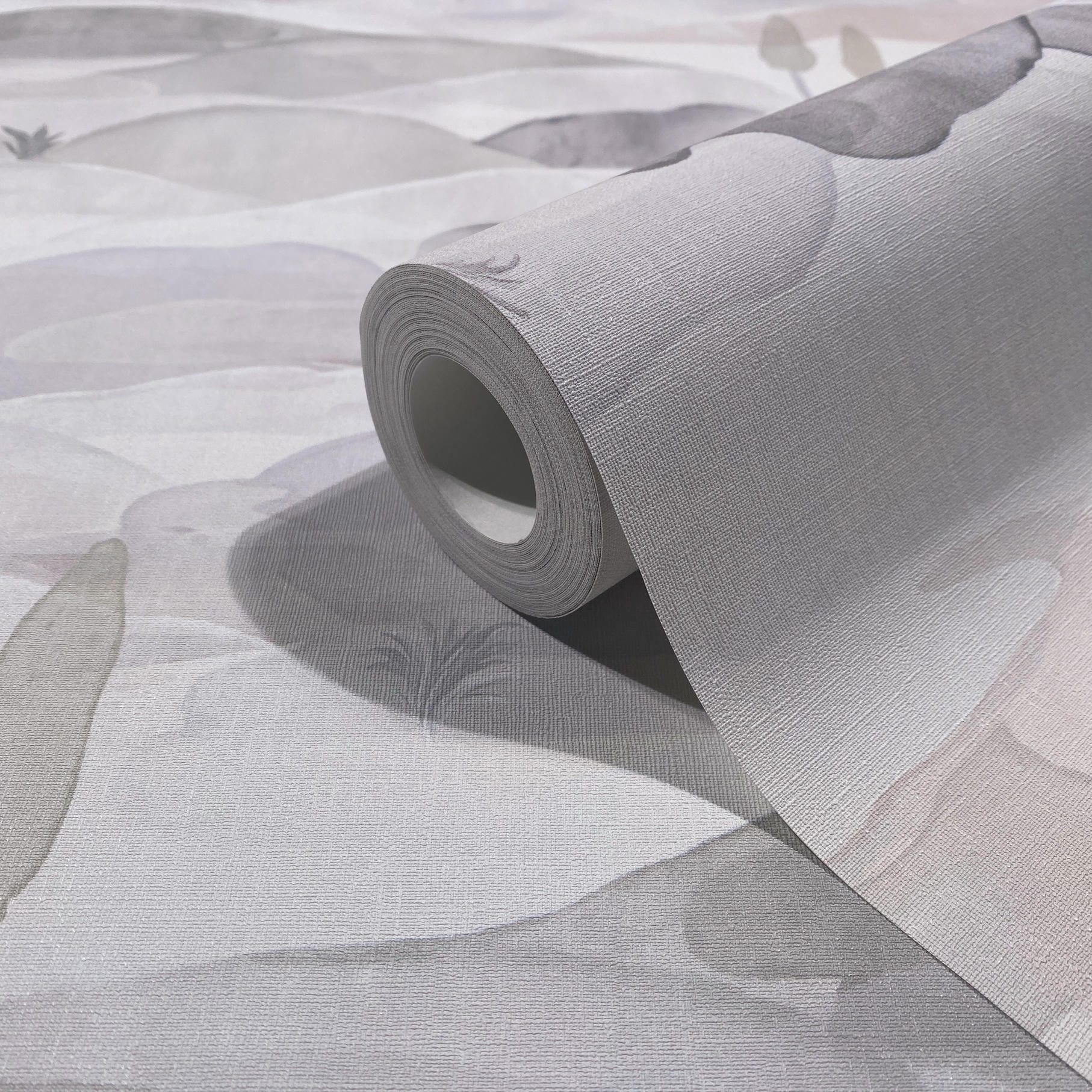 Marburg Boho 35787 Close-up of a wallpaper roll on the matching surface, showing a grey and white abstract pattern with a fine woven texture.