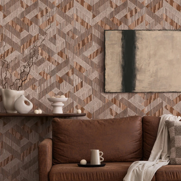 Marburg Boho 35789 Geometric brown and taupe wallpaper with interlocking angled bands and fine vertical striations, shown behind a brown leather sofa with a pillow and throw, a floating shelf with white ceramic vases and branches, small decorative spheres, a mug on a tray, and a.
