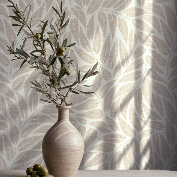 Marburg Boho 35795 Beige leaf-pattern wallpaper with a subtle woven texture, styled with a ceramic vase holding an olive branch and a few olives on a tabletop.