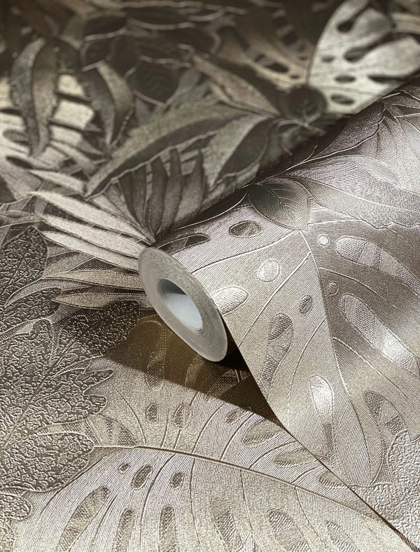 Marburg Botanica 33303 Close-up of a wallpaper roll on matching unrolled paper showing an embossed metallic gold tropical leaf pattern with large monstera leaves.