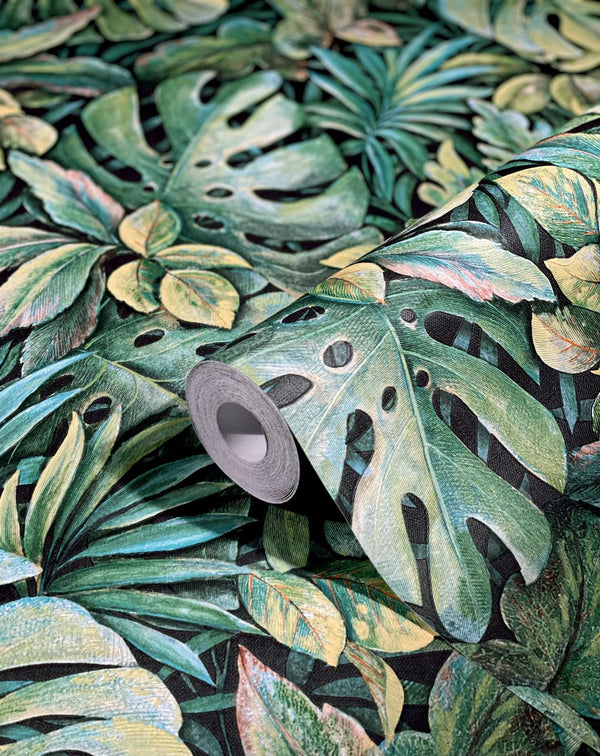 Marburg Botanica 33304 Close-up of a wallpaper roll resting on matching wallpaper printed with large tropical leaves in green tones on a dark background, showing surface texture.