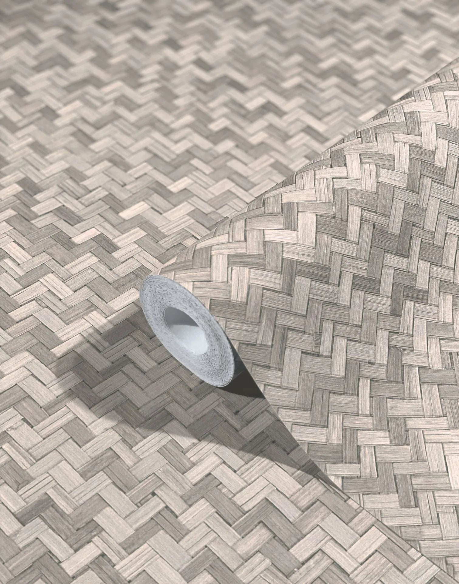 Marburg Botanica 33311 Roll of wallpaper unrolled across a surface showing a beige and gray basketweave pattern with woodgrain-like texture; inner core and shadow visible.