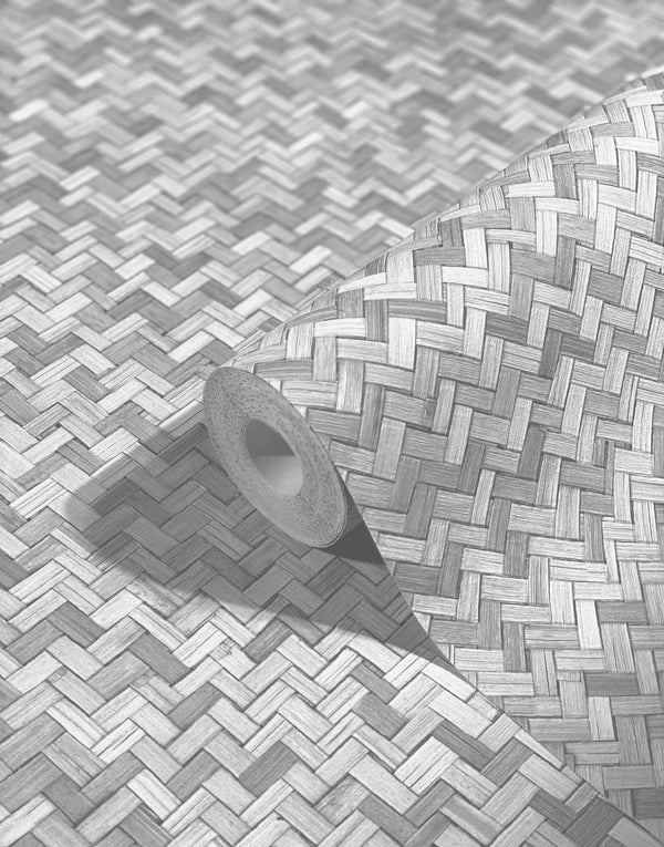 Marburg Botanica 33314 A wallpaper roll resting on matching wallpaper showing a woven herringbone basketweave pattern in gray tones, with the roll core and its shadow visible.