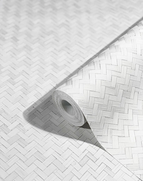 Marburg Botanica 33315 Close-up of a wallpaper roll with a white woven herringbone-style pattern resting on the same patterned surface, casting a soft shadow.