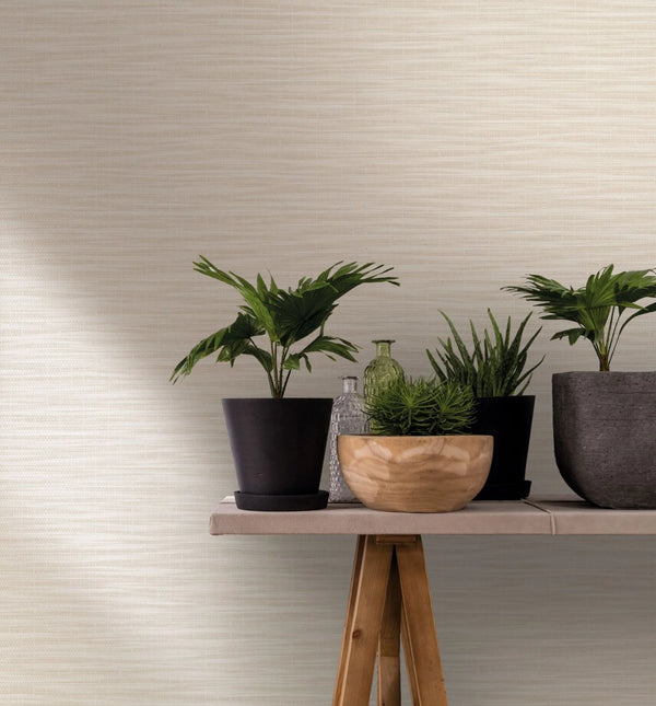 Marburg Botanica 33318 Beige and white wallpaper with subtle horizontal striations. In front, a trestle table holds potted plants, a wooden bowl, and clear and green glass bottles.