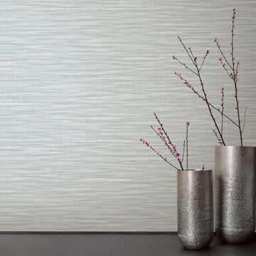 Marburg Botanica 33321 Light green and white horizontally striated wallpaper behind two tall metal vases with pink flowering branches on a dark surface.