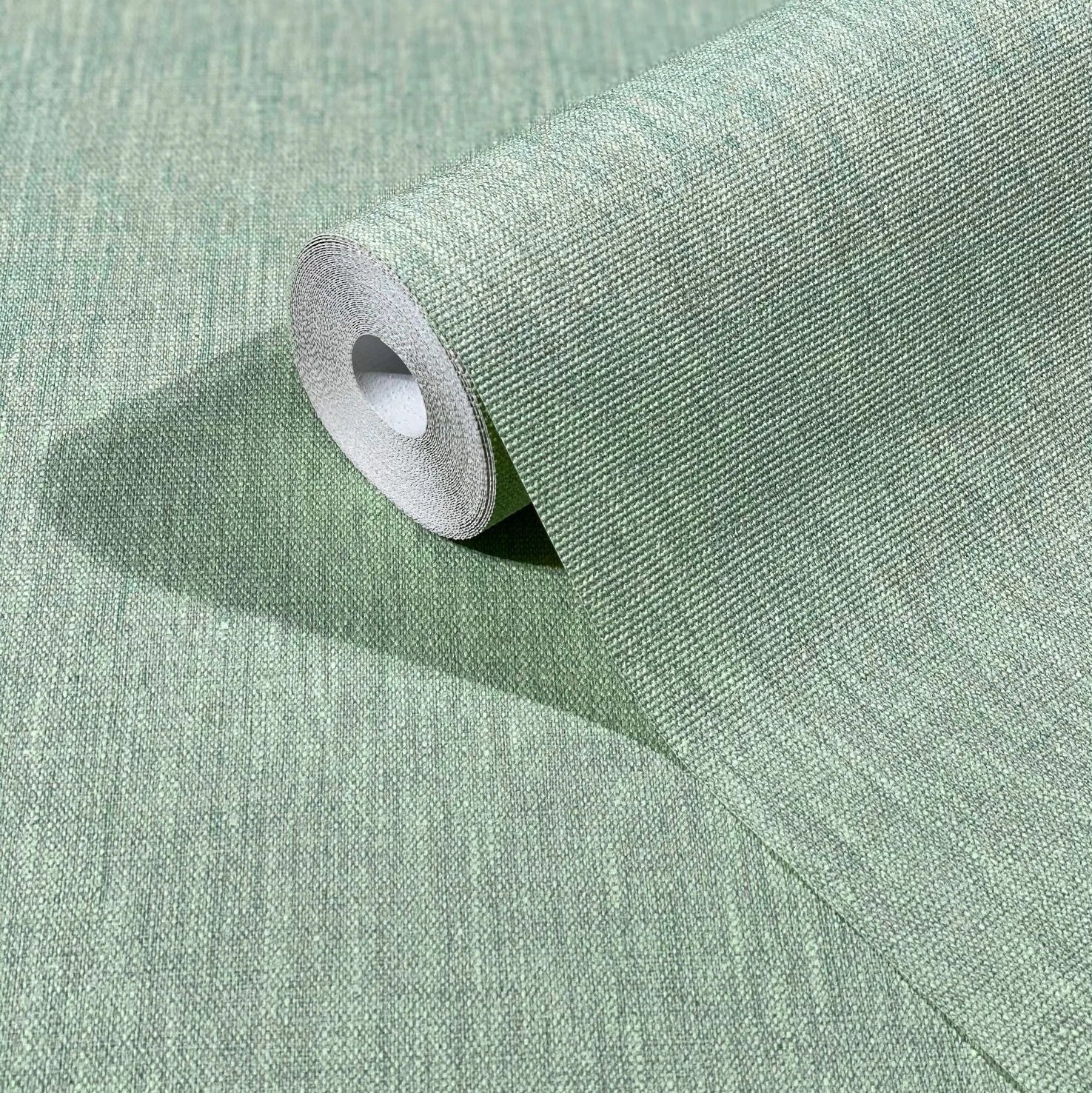 Marburg Botanica 33331 A green textured wallpaper roll partially unrolled on a matching surface, showing a fine woven-look pattern.