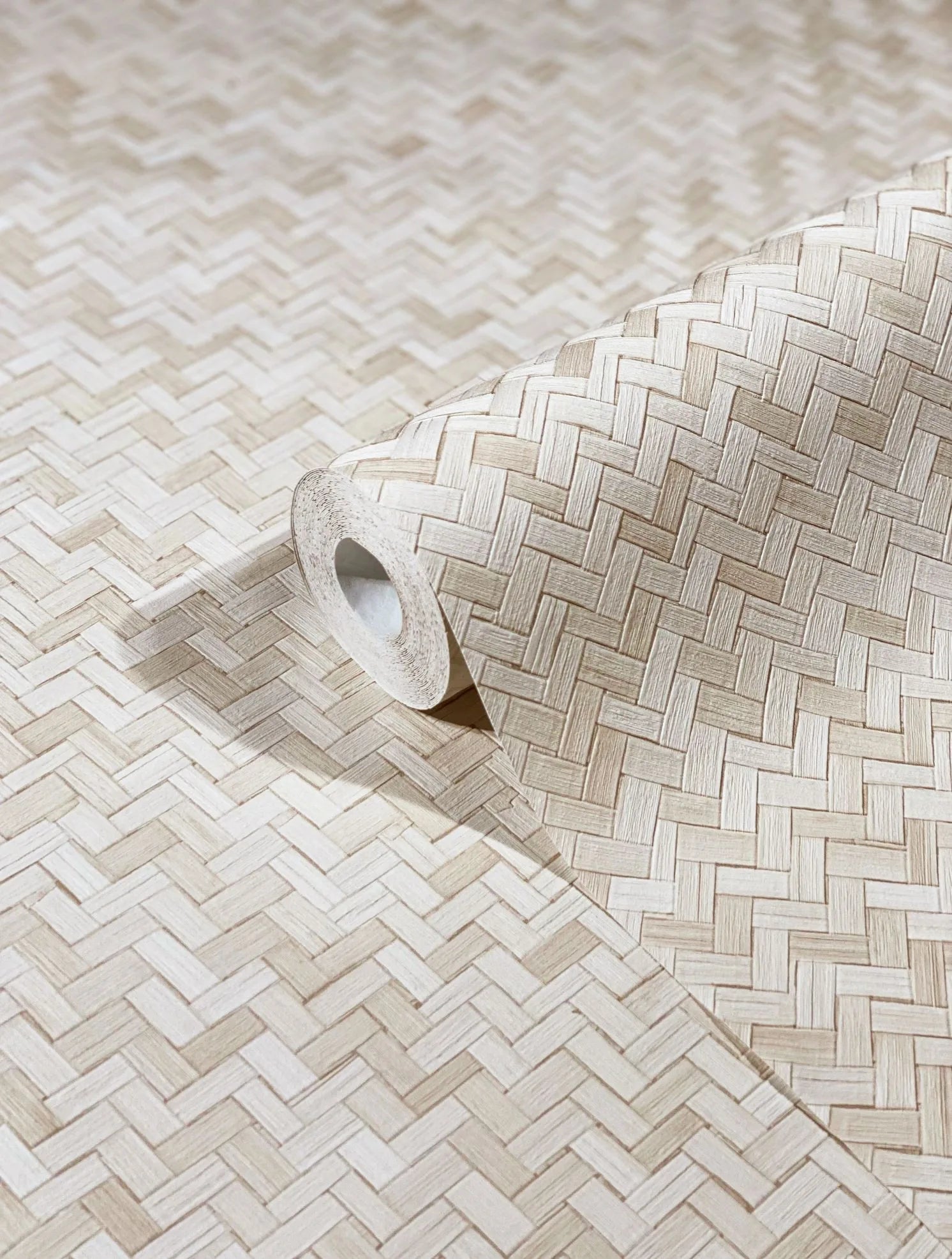 Marburg Botanica 33333 Close-up of a wallpaper roll with a beige basket-weave herringbone pattern resting on the same unrolled wallpaper.