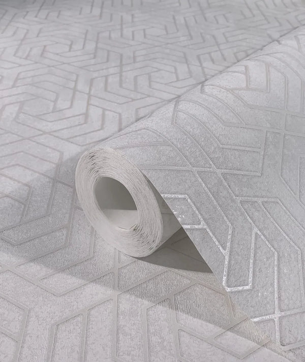Marburg City Glam 32606 Close-up of a gray geometric patterned wallpaper roll resting on a matching unrolled sheet, showing embossed angular lines.